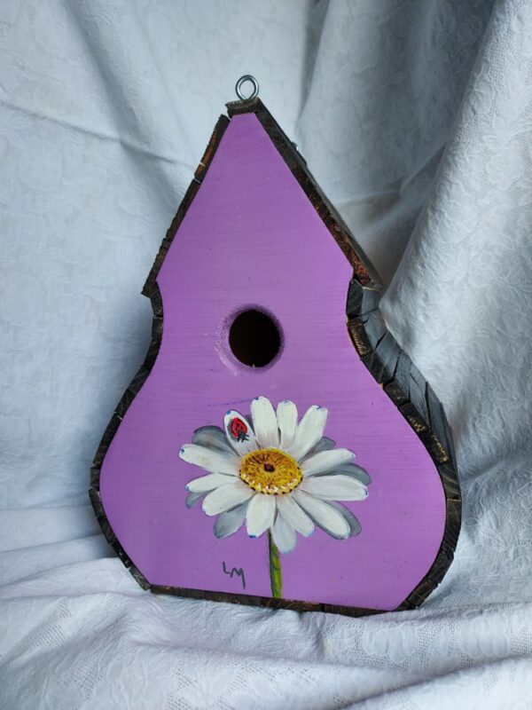 A purple birdhouse with a sunflower painted on it.